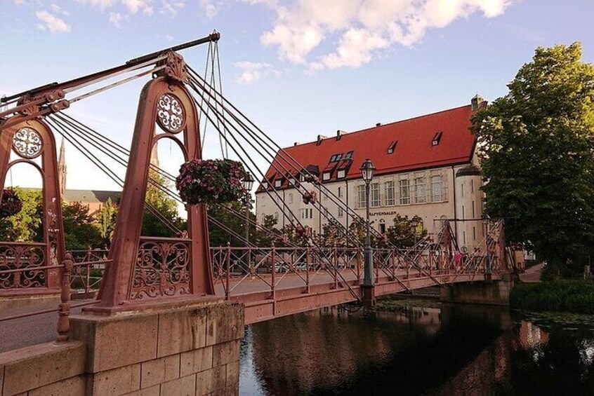 Un puente con ornamentación metálica y un edificio con techo rojo al fondo. 1