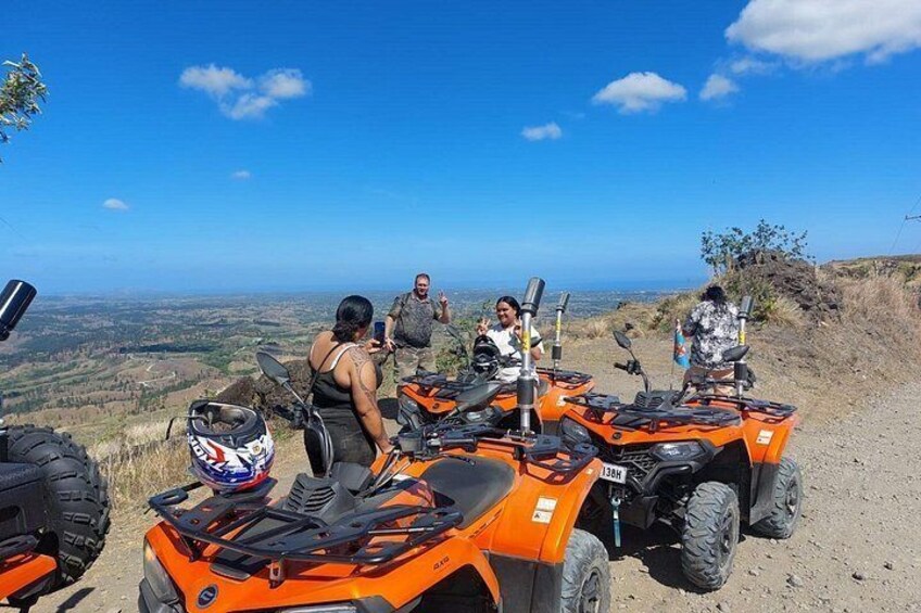 Een groep mensen op een heuvel met uitzicht over een landschap, met ATVs op de voorgrond. 5