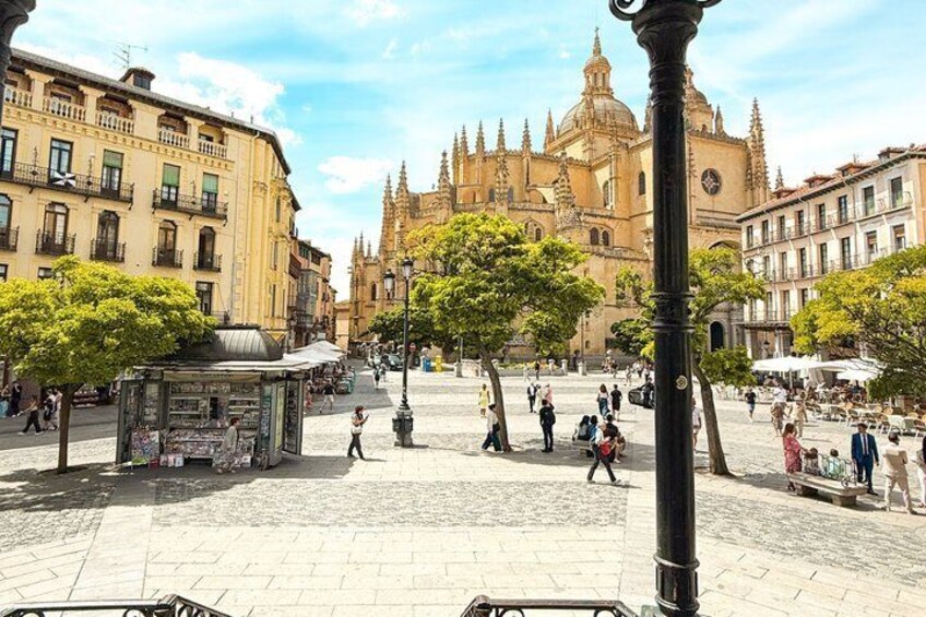 A plaza with a large cathedral in the background, surrounded by historic buildings and trees. 5