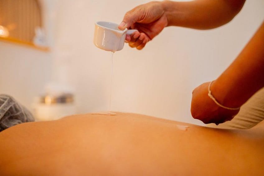 A person pouring a liquid from a mug onto another person's back. 4