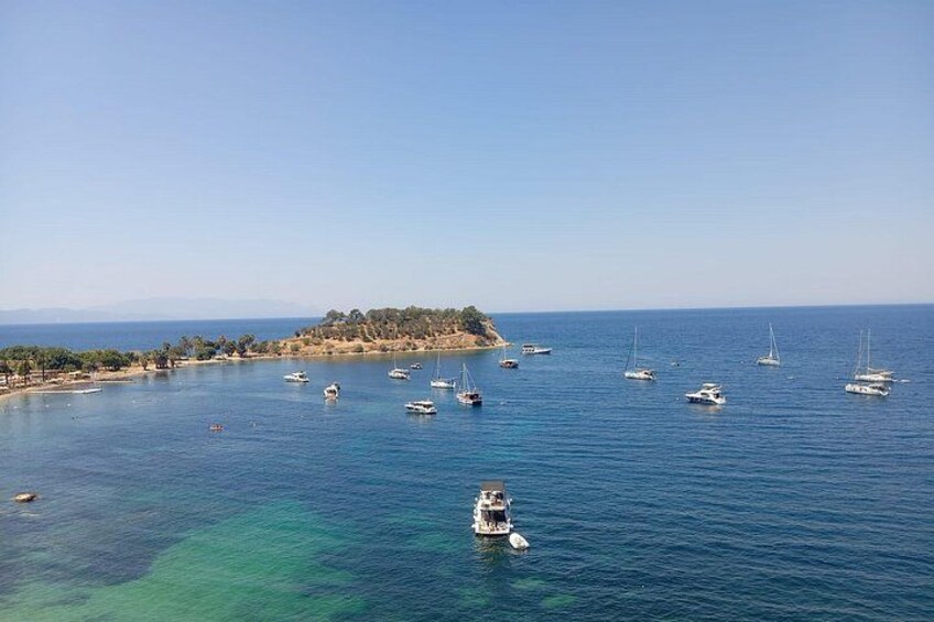 A coastal scene with boats on calm waters, a small island with trees, and a clear sky. 4