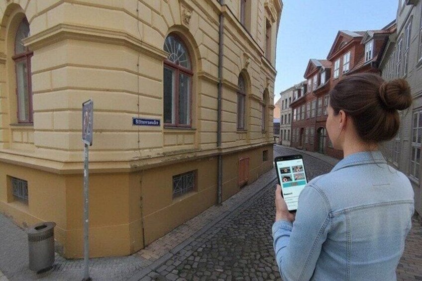 A person using a smartphone in a cobblestone street with historic buildings. 3