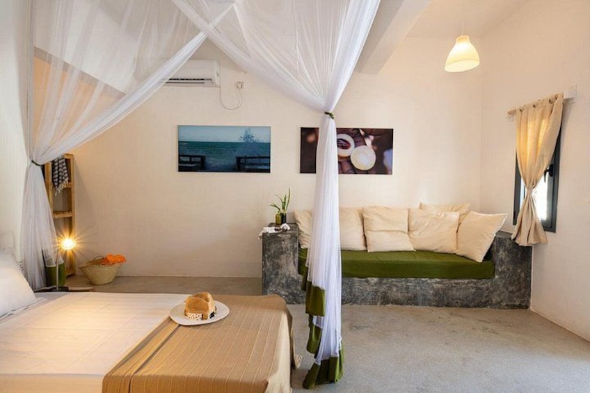 A bedroom with a bed, a sofa, a dining table with a plate, and a window with curtains. 2