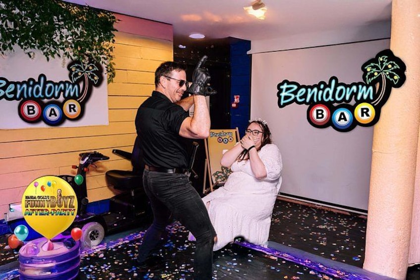Ein Mann mit schwarzem Hemd und Jeans, eine Frau in einem weißen Kleid und ein Schild mit der Aufschrift Benidorm Bar. 3