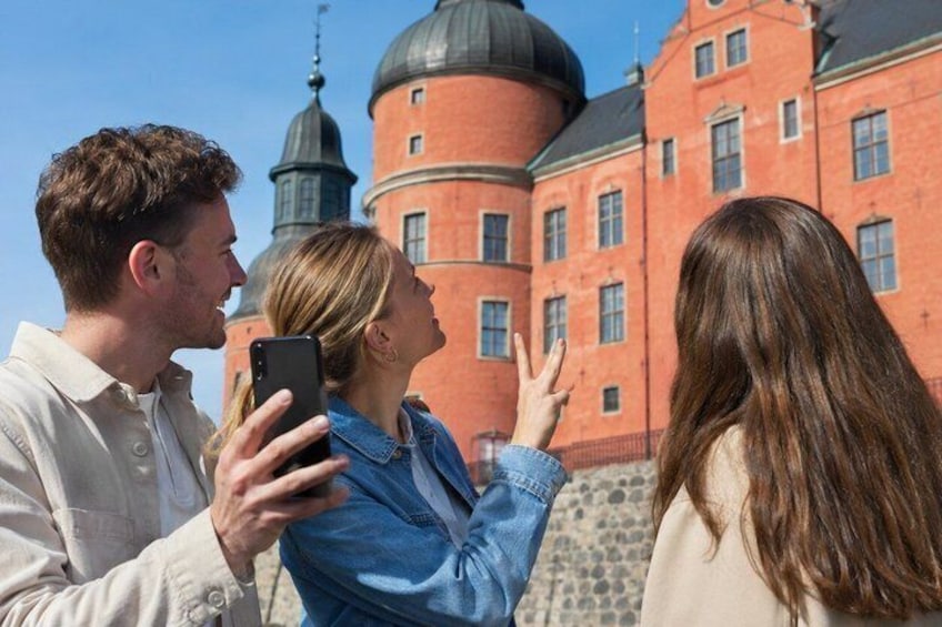 Three people taking a photo of a red brick building with domes. 3