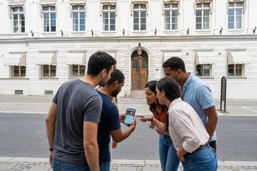 A group of people standing on a sidewalk, looking at a smartphone. 2