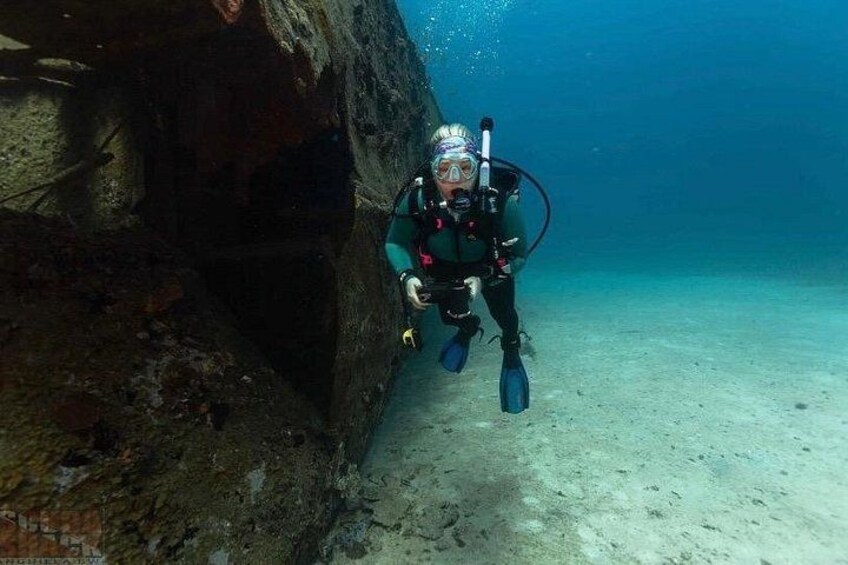 A diver exploring an underwater cave with a rocky wall. 2