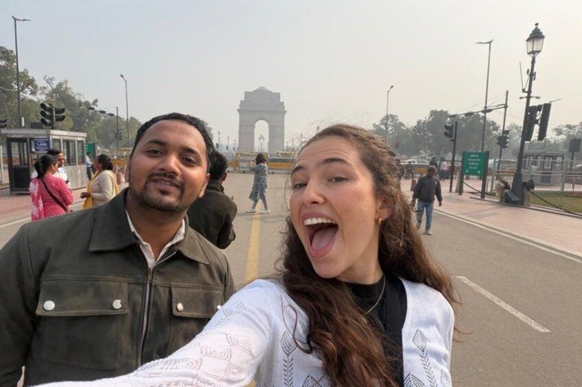 Two people taking a selfie with the India Gate in the background. 1