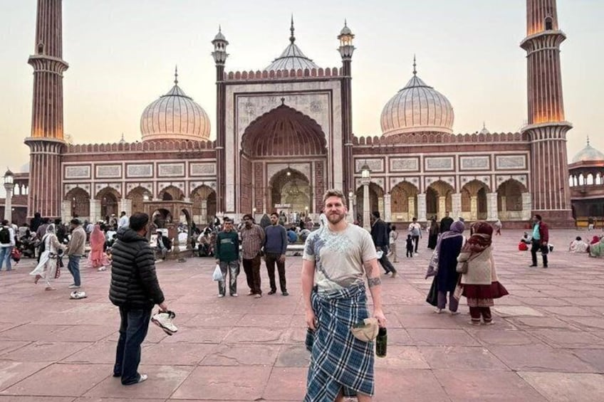 Ein historisches Gebäude mit Kuppeln und Minaretten, eine Menschenmenge und ein Mann in traditioneller Tracht. 1