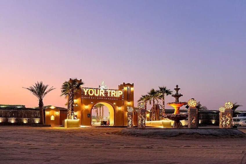 A well-lit archway with 'YOUR TRIP' signage, palm trees, and decorative lighting. 5
