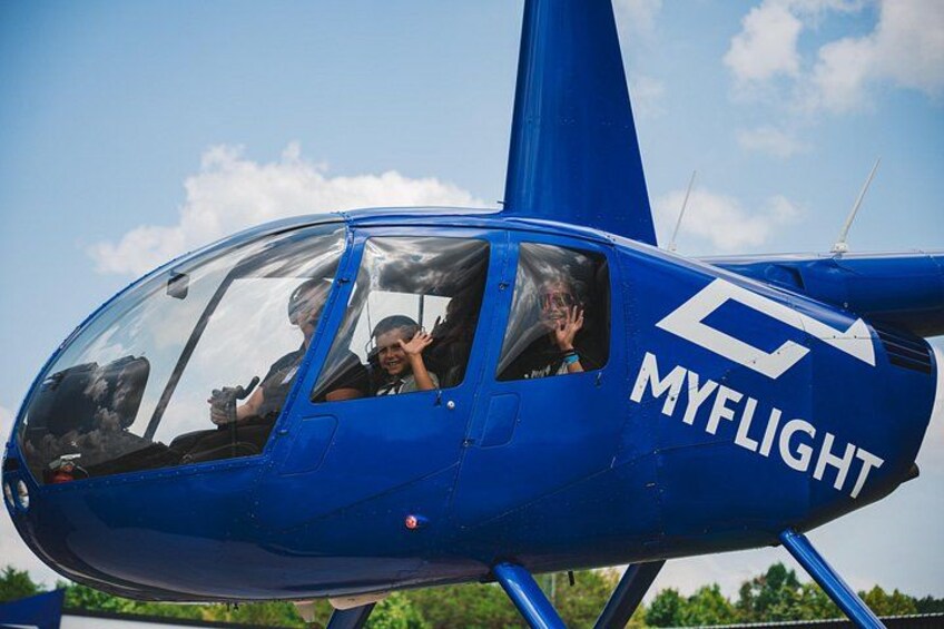 A blue helicopter with the text 'MYFLIGHT' on its side, parked outdoors with a clear sky in the background. 1
