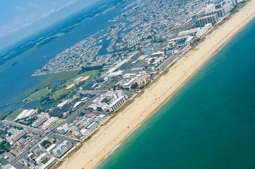 An aerial view of a coastal city with a long beachfront, dense urban area, and a large body of water. 5