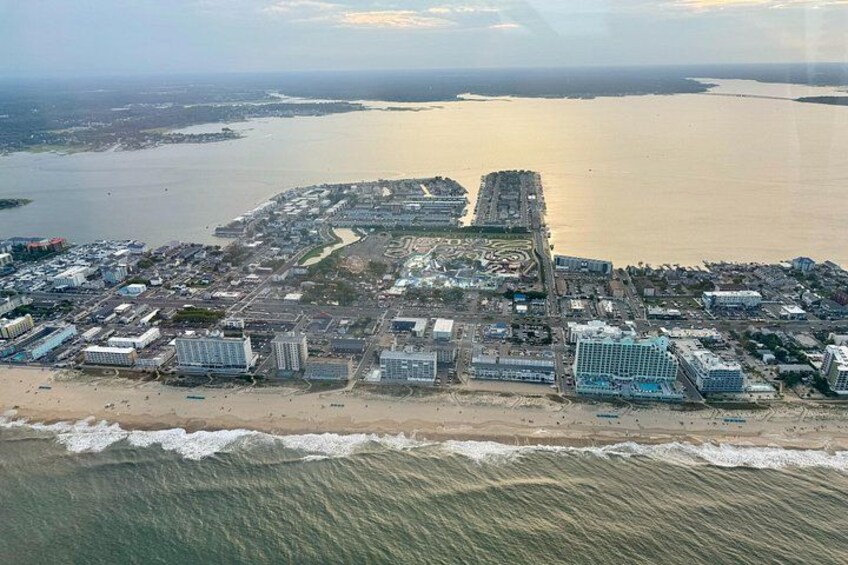 An aerial view of a coastal city with a beach, buildings, and a large body of water. 4