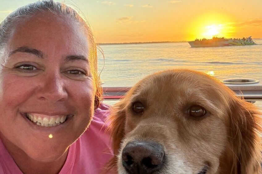 Un coucher de soleil sur l’eau, avec un bateau et un chien. 3