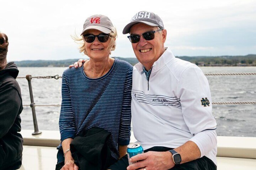 Two people sitting on a boat with a body of water and a distant shoreline in the background. 2