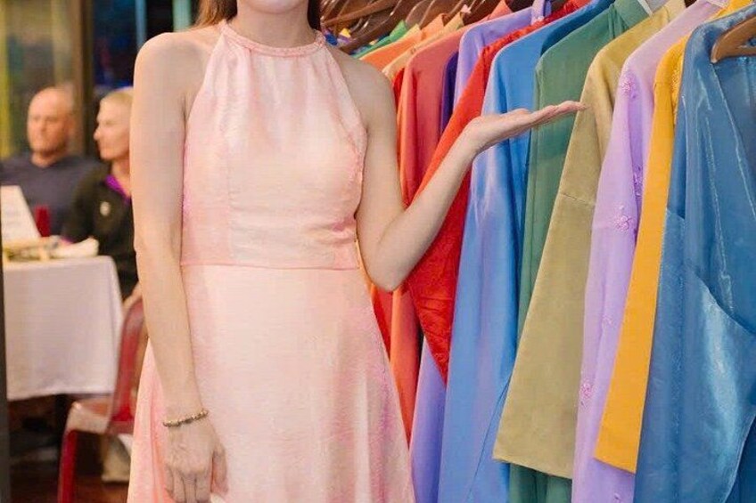 Eine Person in einem rosa Kleid steht vor einem Kleiderständer voller bunter Kleider. 4