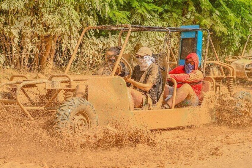 A vehicle driving through a muddy area with people inside. 2