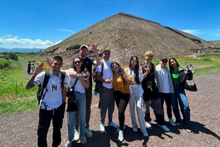 A group of people posing in front of a large pyramid-like structure. 4