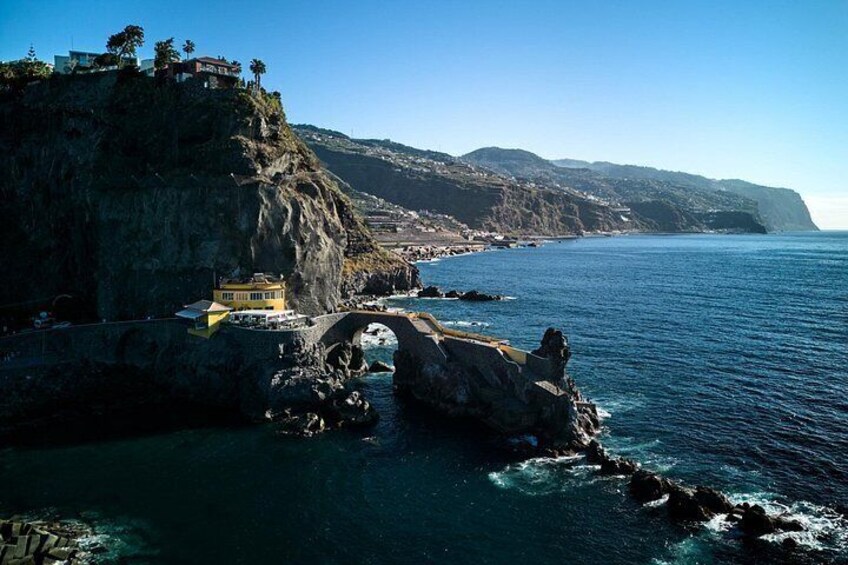 Un paysage côtier avec un pont, un bâtiment jaune et des falaises rocheuses. 4