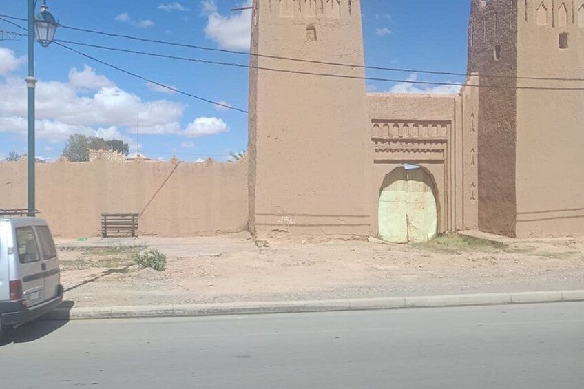 A beige building with a large arched entrance, a street lamp, and a parked van. 5