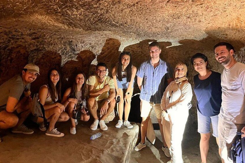 A group of people inside a cave with rocky walls and a rough floor. 4