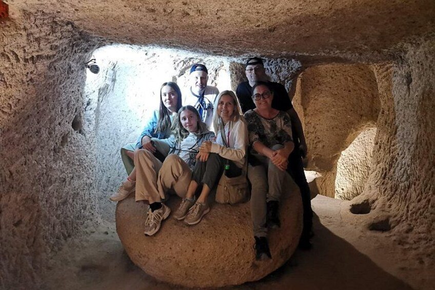 A group of people sitting on a large rock inside a cave. 1