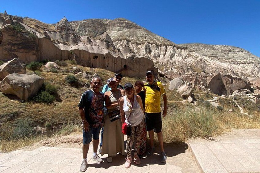 A group of people standing on a paved path with a rocky landscape and large boulders in the background. 2