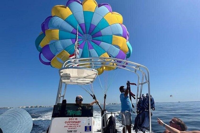 Parasailing med et farverigt faldskærm, en båd og en klar blå himmel. 2
