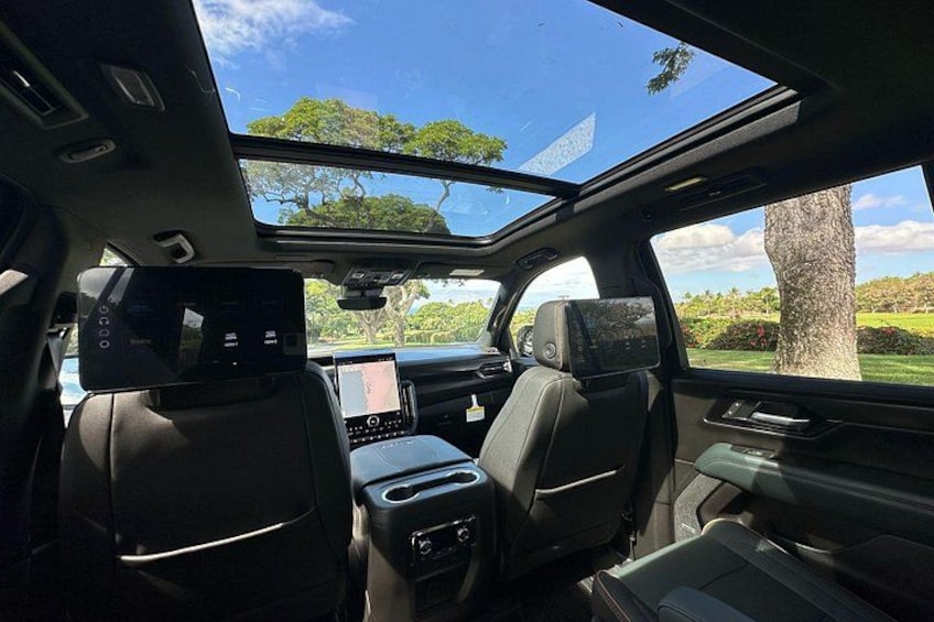 Interior de coche con techo solar, asientos de cuero, pantalla táctil central y tablero de control con varios mandos. 2
