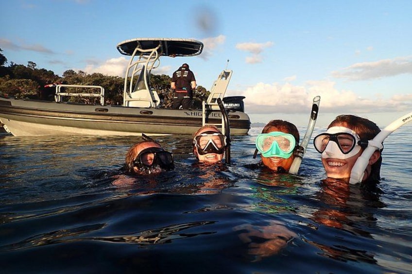 Three people snorkeling in calm water with a boat in the background. 1