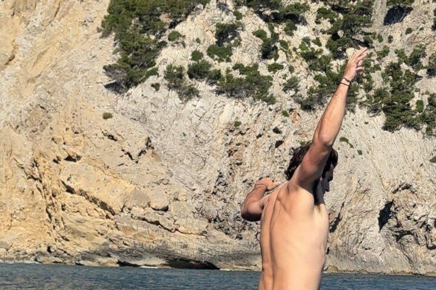 A person diving into a body of water with a rocky cliff in the background. 4