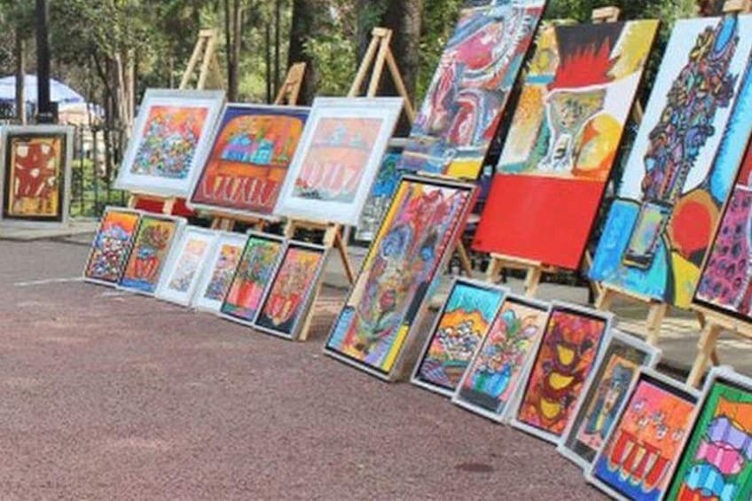 A series of colorful paintings displayed on easels in an outdoor setting. 2