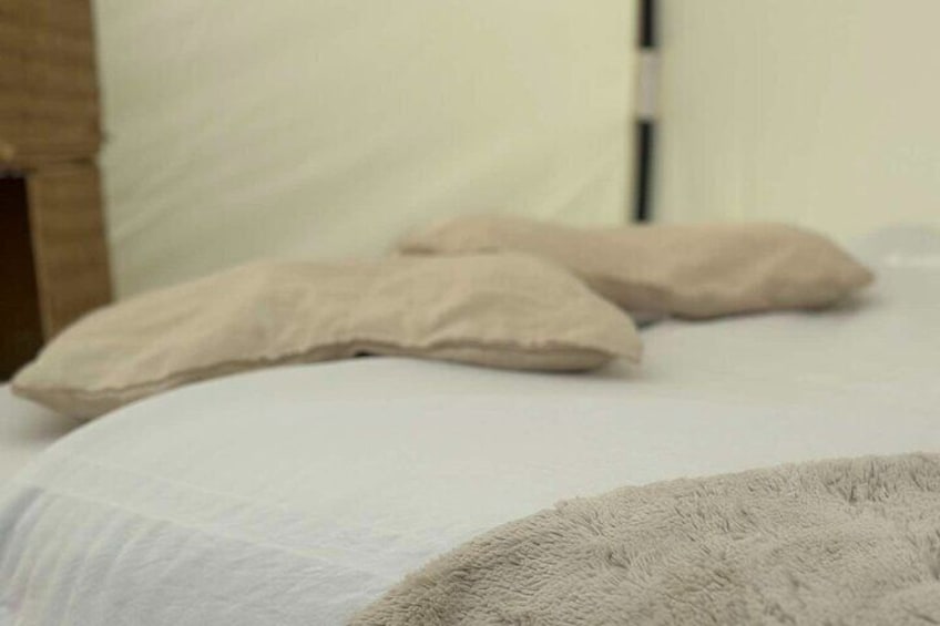 A bed with white sheets and two beige pillows. 4