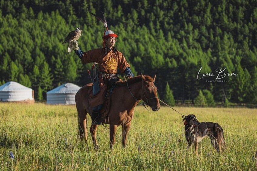 A person on horseback in a grassy field with yurts in the background. 4