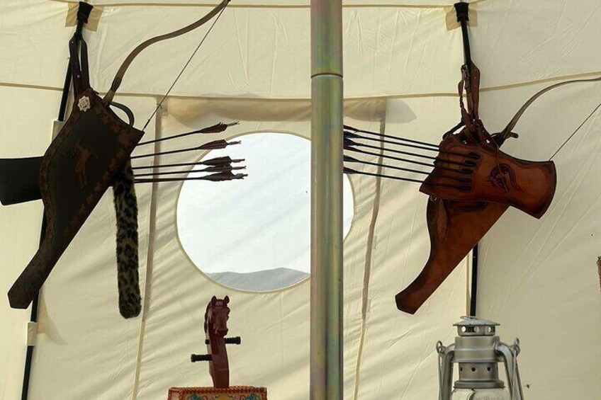 A tent with two wooden hand-shaped objects hanging from the ceiling, a lantern, and a circular object in the center. 3