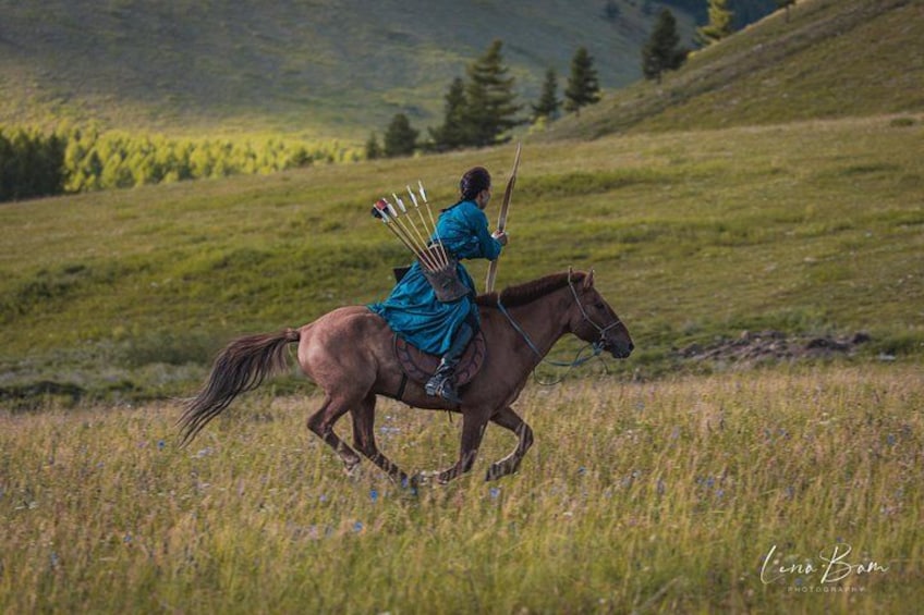 A person riding a horse in a grassy field with a bow and arrows. 5