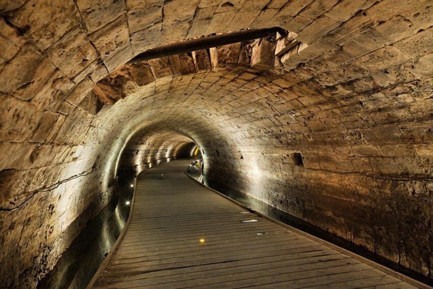 A stone tunnel with a wooden walkway. 3