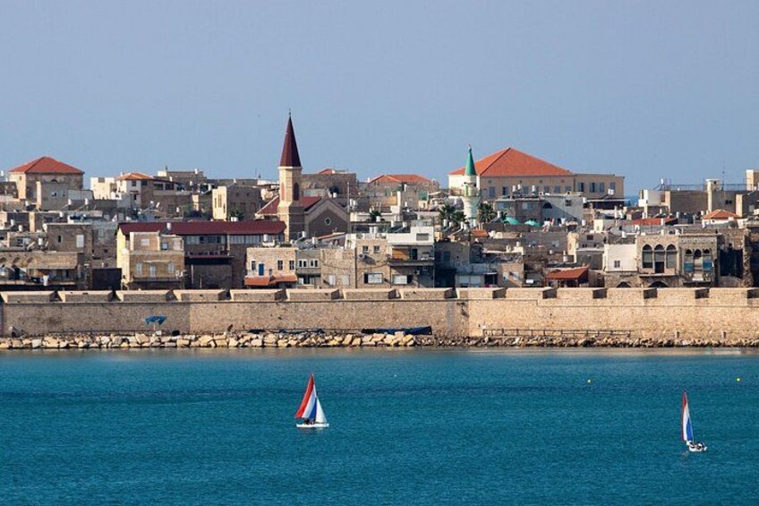 A coastal town with buildings, a prominent church with a tall spire, and sailboats on the water. 2
