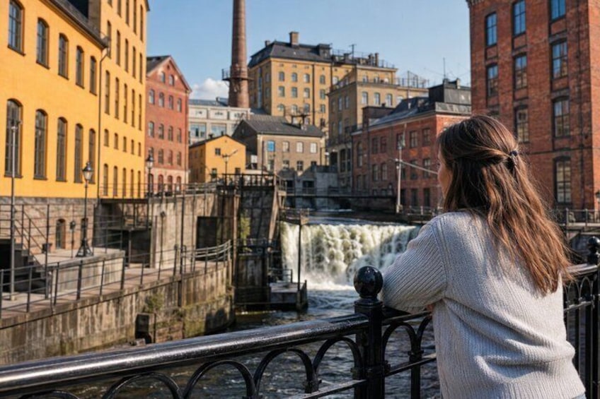 A person overlooking a waterfall with industrial buildings in the background. 2