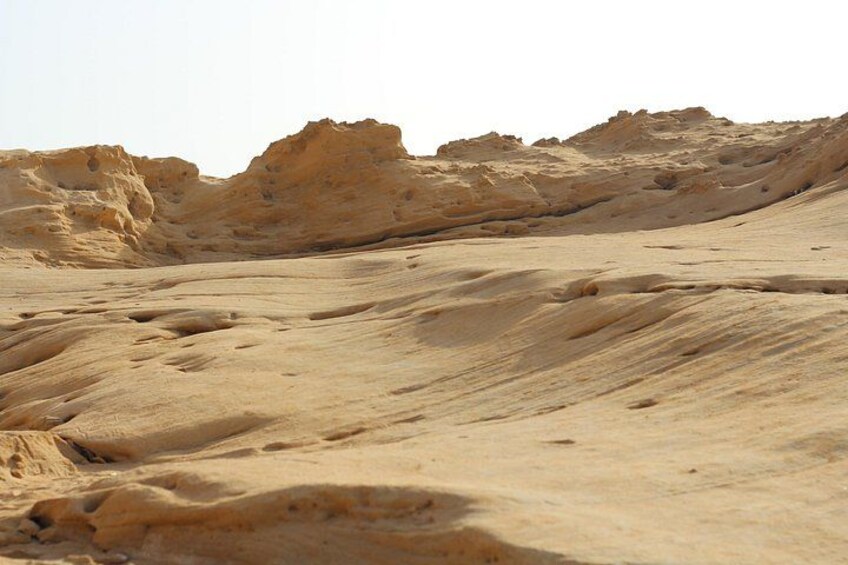 A desert landscape with sand dunes and rocky outcrops. 4