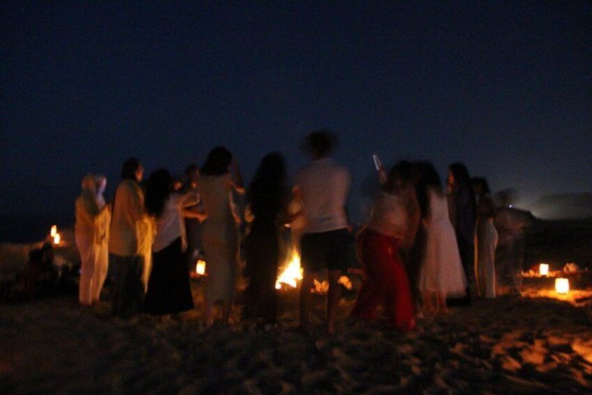 A group of people gathered around a fire at night on a beach. 5