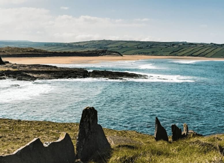 A coastal landscape with a sandy beach, rolling hills, and distinctive rock formations. 2