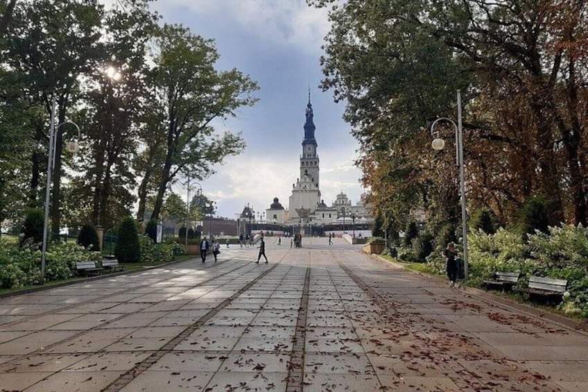 A paved square with benches, trees, and a distant building with a spire. 3