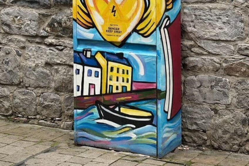 A colorful mural with a warning sign, buildings, and a boat. 1