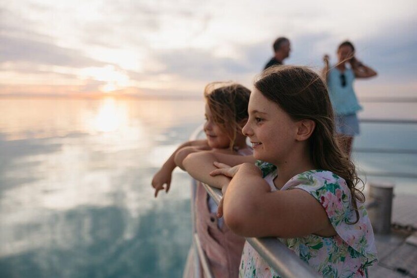A sunset over a body of water with people standing on a pier. 4
