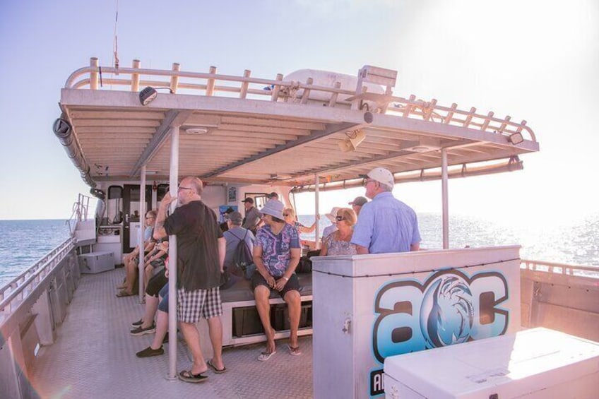 A group of people on a boat with a covered deck and graffiti on the side. 2