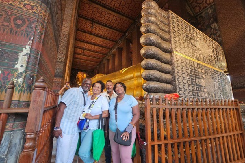 A group of people standing in front of a large golden structure with intricate patterns, possibly a religious or historical monument. 2