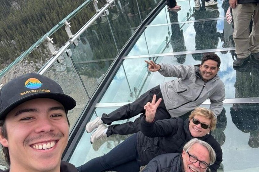 Mensen op een glazen brug, met een bergachtig landschap op de achtergrond. 5