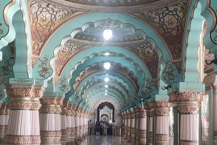 An ornate corridor with intricate ceiling designs and columns. 4