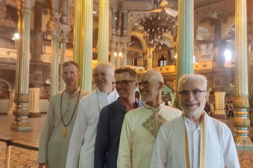 A group of people in a historical building with ornate columns and chandeliers. 3